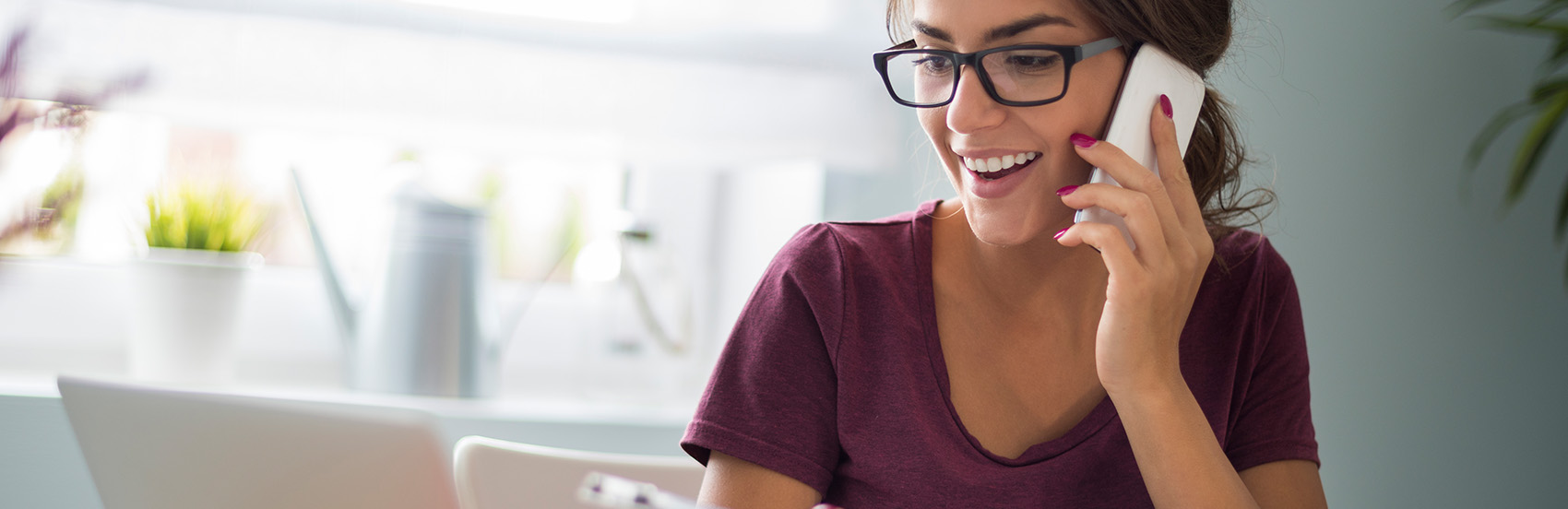 young brunette woman wearing glasses and talking on the phone with her dentist in haymarket